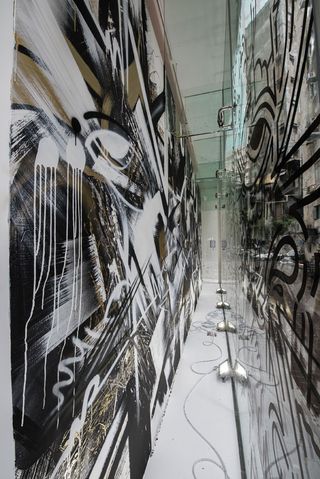 The gallery's ground floor and glass facade present a diverse range of murals and paintings in dark grey and black.