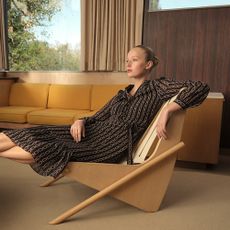 Model wearing Hobbs dress lounging on an abstract armchair