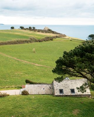 coastal view with fields and trees and stone barn conversion in foreground