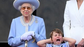 Britain's Prince Louis of Cambridge (R) holds his ears as he stands next to Britain's Queen Elizabeth II to watch a special flypast from Buckingham Palace balcony following the Queen's Birthday Parade, the Trooping the Colour, as part of Queen Elizabeth II's platinum jubilee celebrations, in London on June 2, 2022