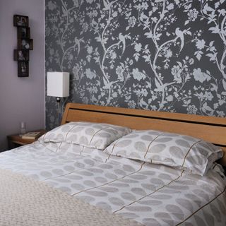 bedroom with floral wallpaper and cushions on bed