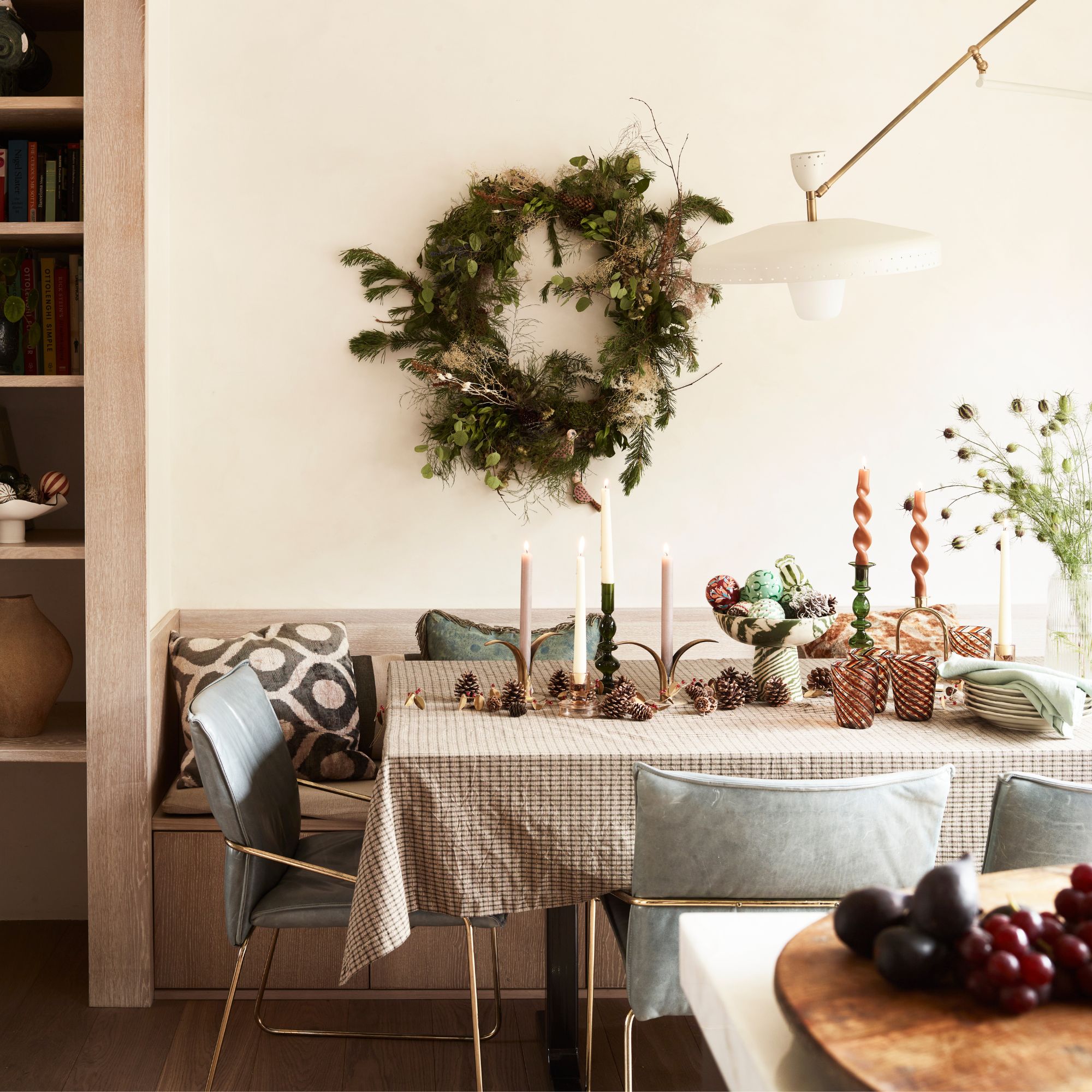 Dining room table decked out with christmas decorations and a wreath on the wall behind it