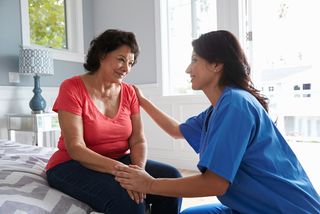 A nurse speaks with a older woman patient