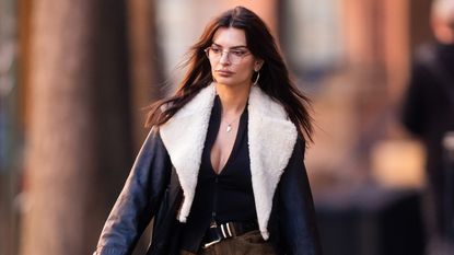 Emily Ratajkowski wearing a fur-lined leather winter coat with plaid pants 