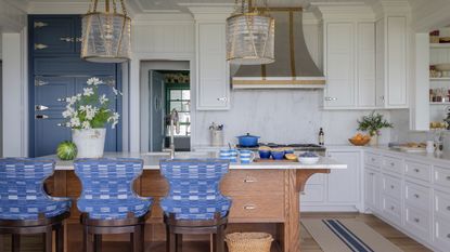 accent colors for a white kitchen, blue and white kitchen with blue bar stools and blue cabinet, metallic accents, white cabinetry, large glass and brass pendants