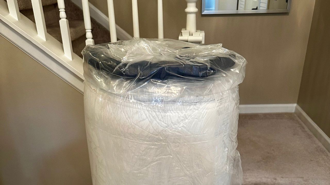 The wrapped Glacier Apex Hybrid mattress removed from its box at the foot of a staircase