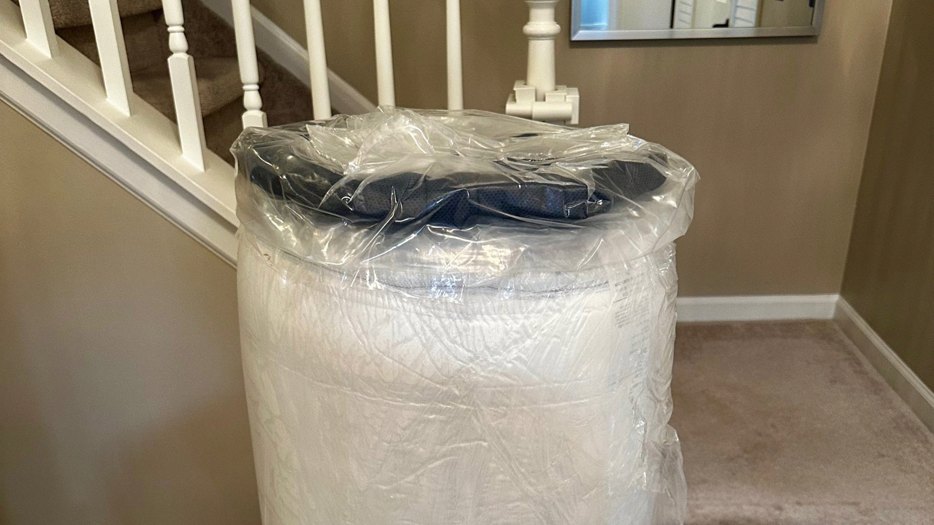 The wrapped Glacier Apex Hybrid mattress removed from its box at the foot of a staircase