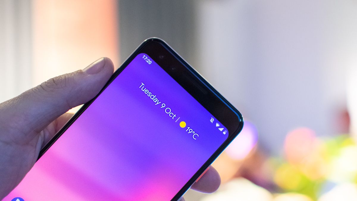 A hand holding a Google Pixel 3 aloft with the home screen showing