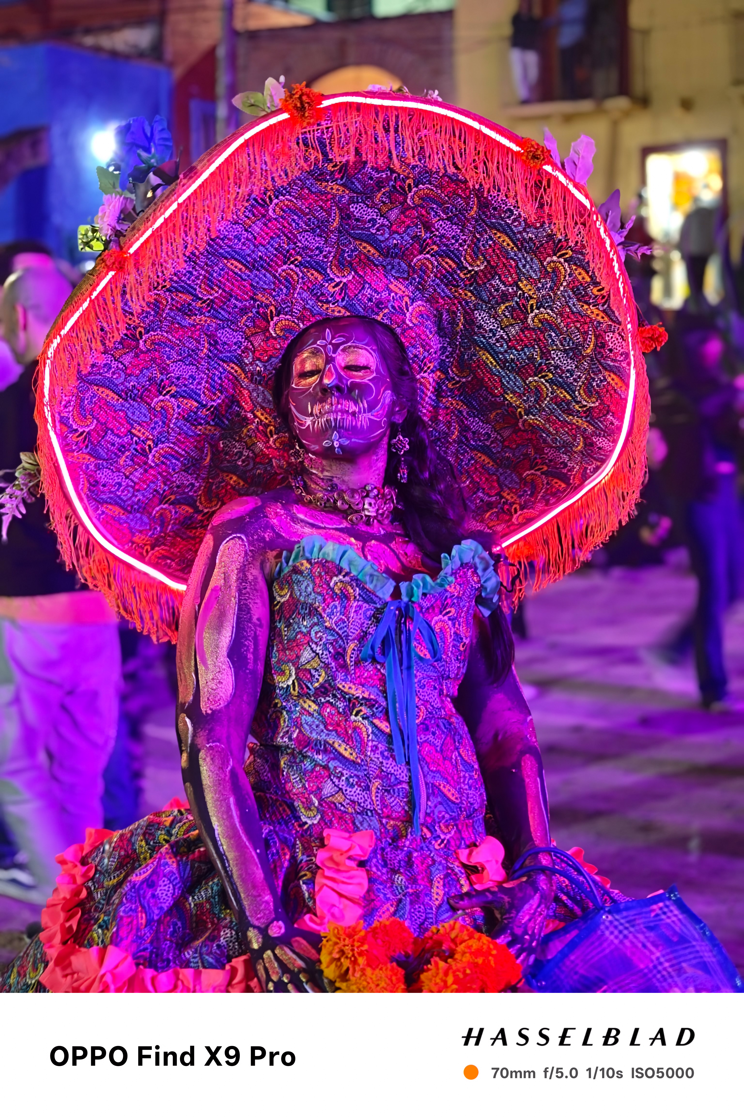 A person wearing a bright luminescent day of the dead outfit at a celebration in Mexico