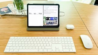 A desk set-up with an iPad Pro, Magic Keyboard, Magic Mouse 2 and AirPods Pro
