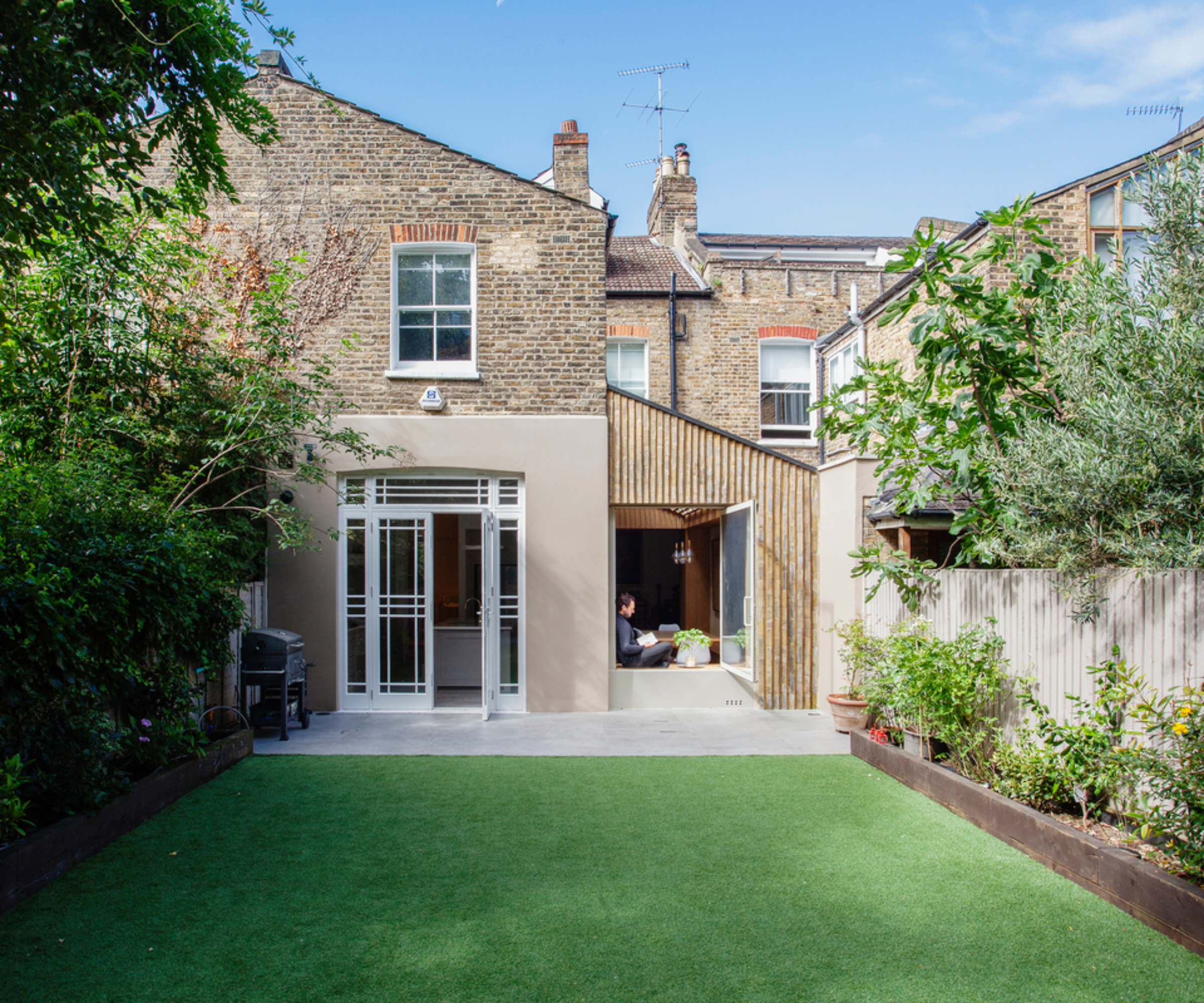 victorian house with side extension with slatted cladding and sloping roof leading to rear lawn and patio
