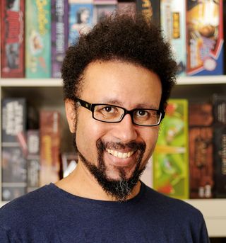 Eric M. Lang smiling in front of board game shelves