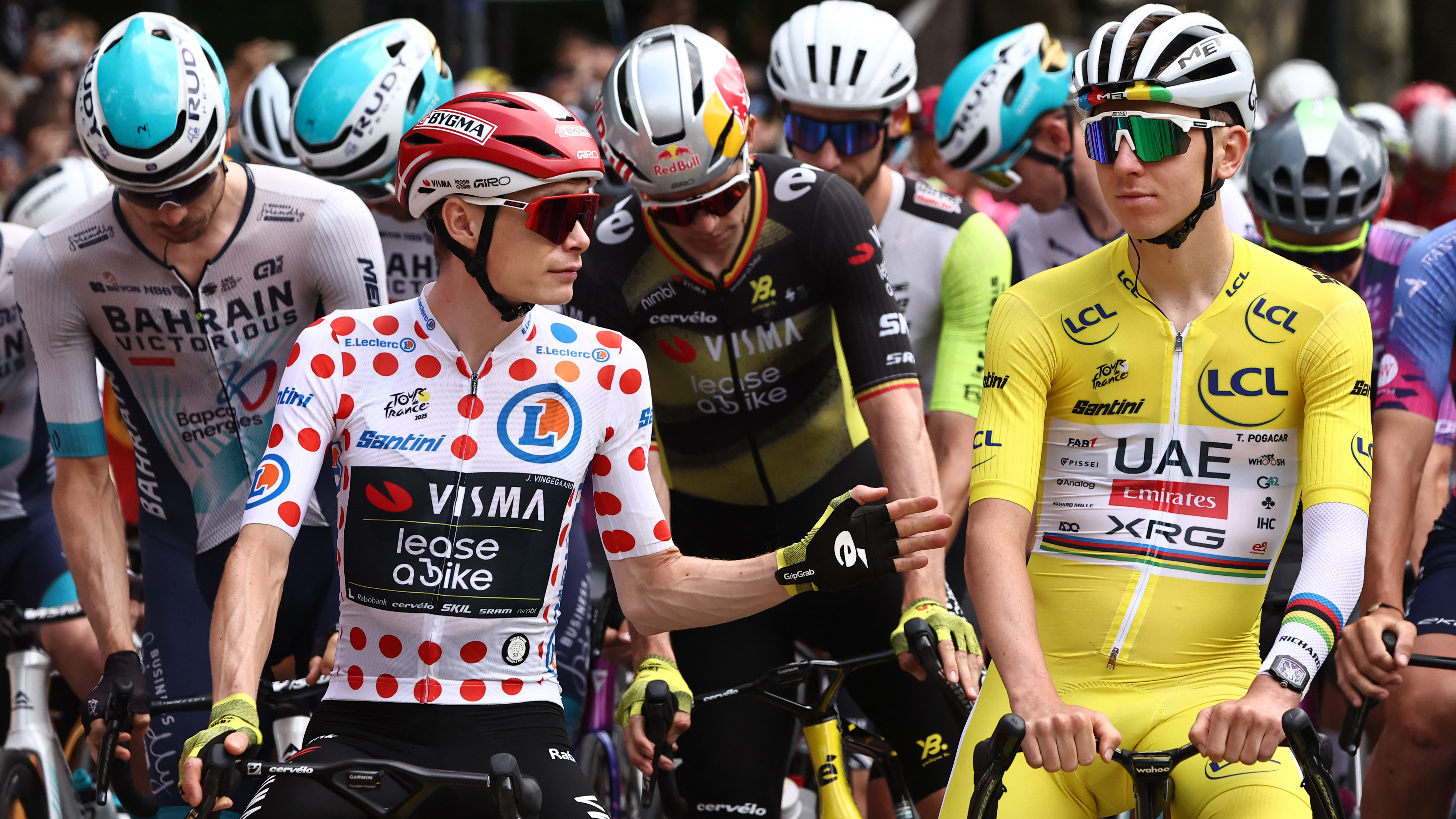 Jonas Vingegaard, wearing the best climber's polka dot jersey, speaks with Tadej Pogacar in the race leader's yellow jersey before the 20th stage of the 2025 Tour de France