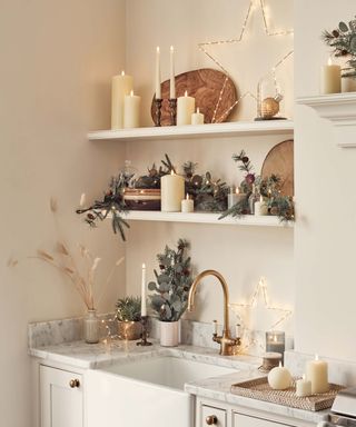 modern kitchen shelving and sink decorated for christmas with lights, foliage and pillar candles