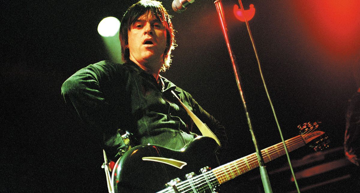 Johnny Marr rests one hand on his hip as he performs onstage with a black Rickenbacker, circa 2003.