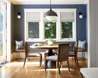 Blue dining room with wooden dining table, wall and pendant lights, chairs and banquette seating