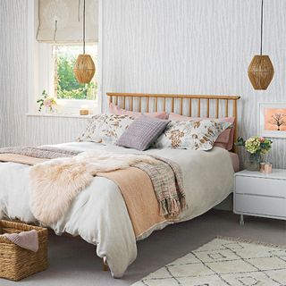 White bedroom with wooden bed and knitted throws and fur