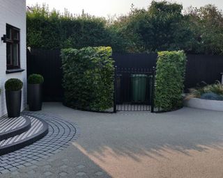 large driveway with bin storage area surrounded by a hedge