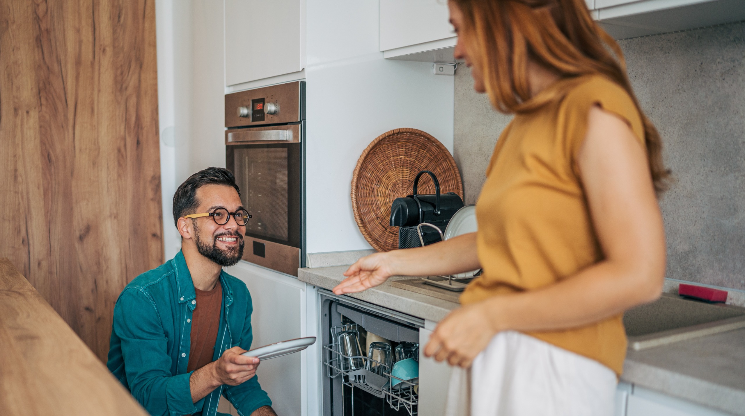 A couple stands in the kitchen doing dishes together.