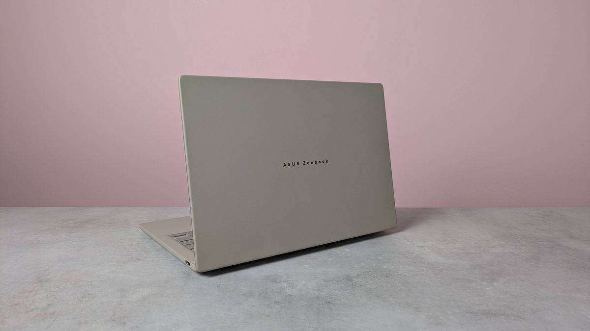Rear three-quarter view of Asus Zenbook A14 on a desk with pink wall in background