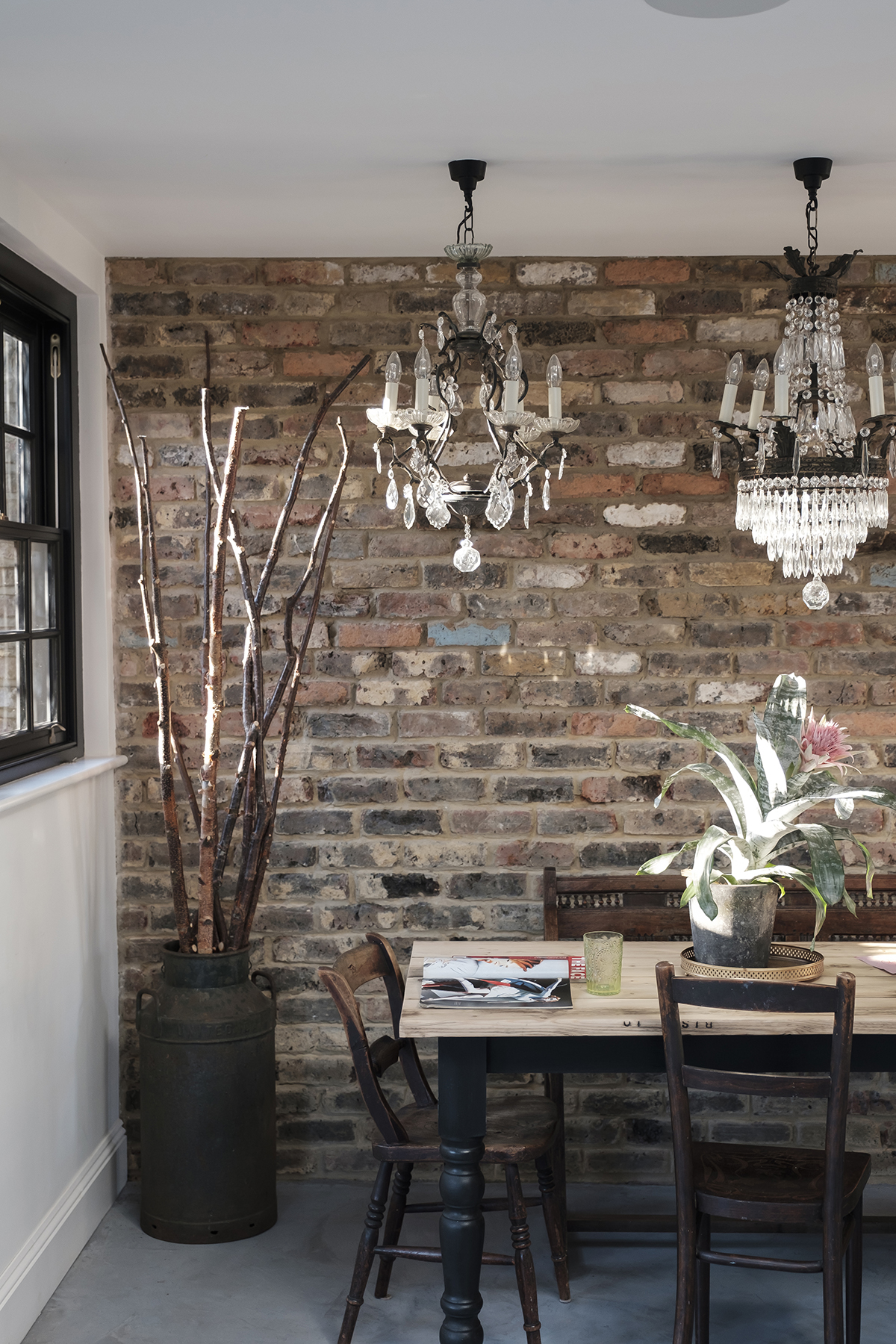 Dining room with exposed brick walls and mismatching chandeliers