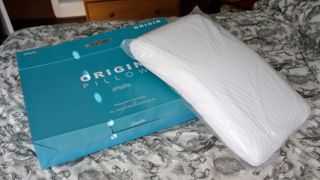 The Origin Coolmax Latex Pillow resting against its box