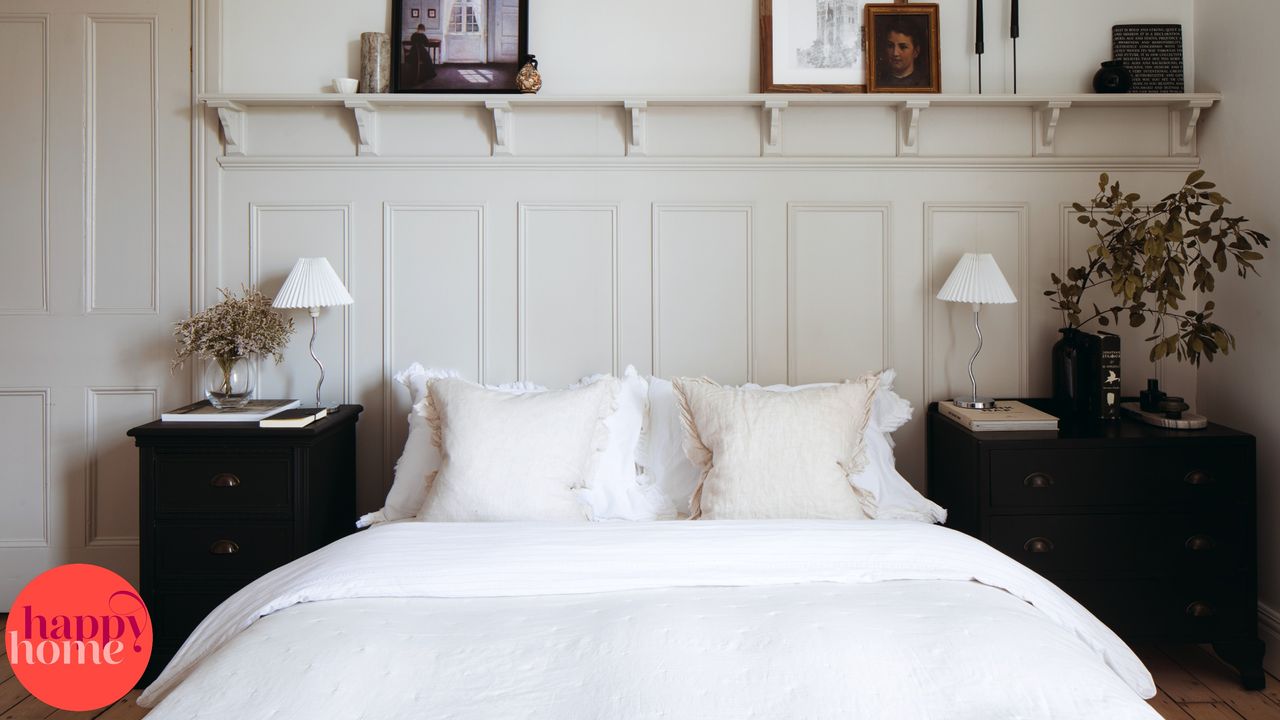 Panelled bedroom wall, double bed with white bedding, two black bedside tables