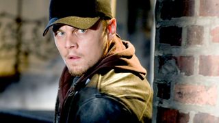 Leonardo DiCaprio as Trooper William "Billy" Costigan Jr. undercover and sneaking next to a wall during a scene in The Departed. 