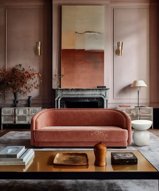 Living room with orange sofa, coffee table, plaster finish walls and gray rug