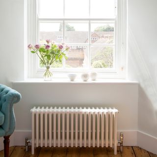 White cast iron radiator underneath windowsill