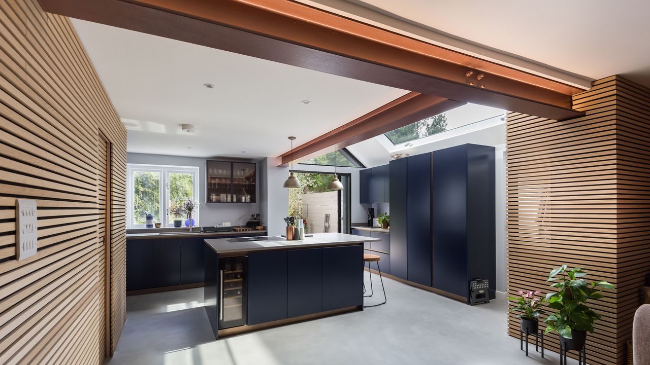 a kitchen with navy blue kitchen cabinetry. kitchen island and a copper coloured RSJ