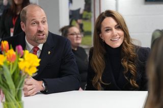 Prince William and Kate Middleton sitting at a table and smiling at the Six Nations rugby match in March 2025