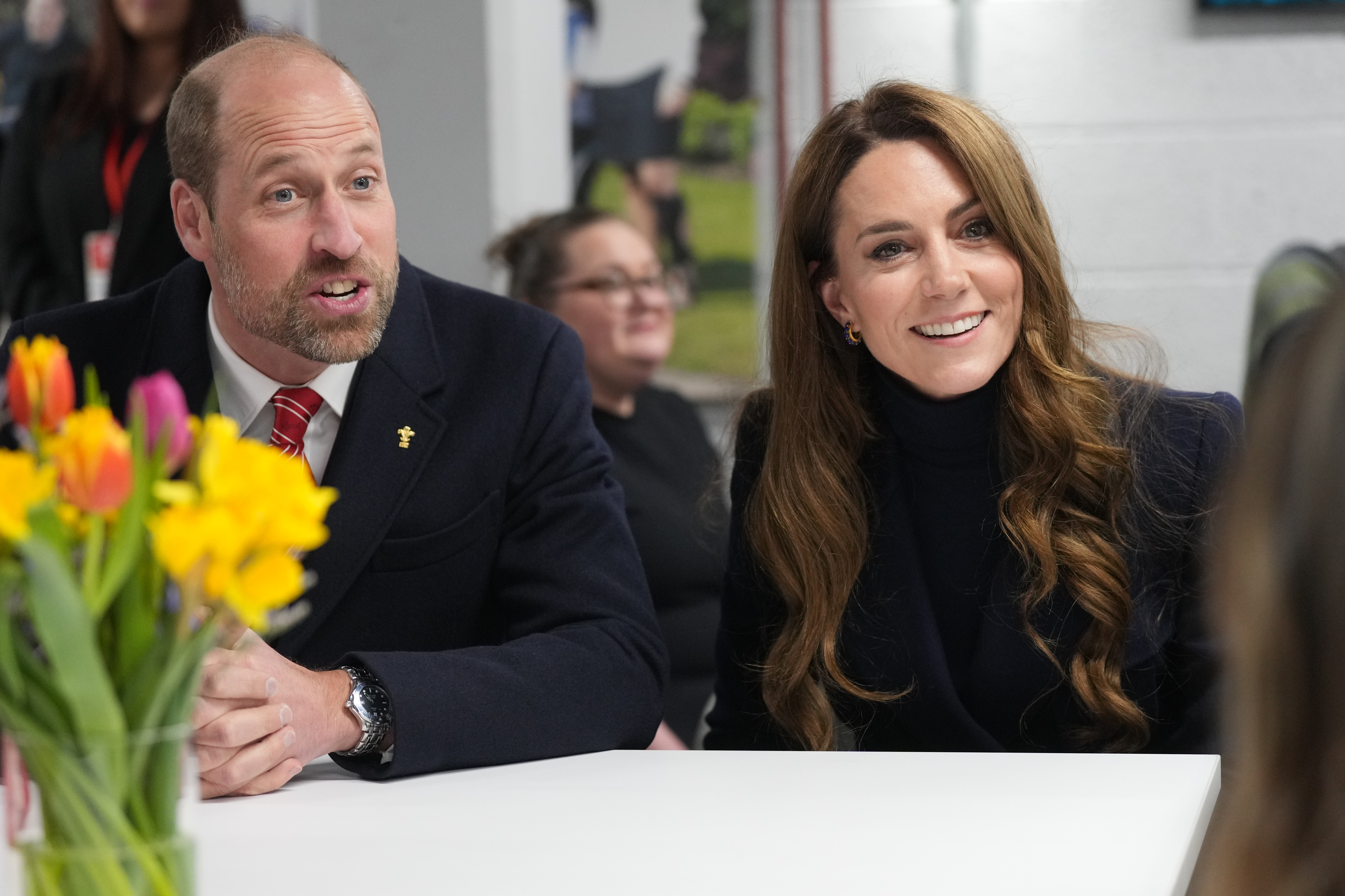 Prince William and Kate Middleton sitting at a table and smiling at the Six Nations rugby match in March 2025