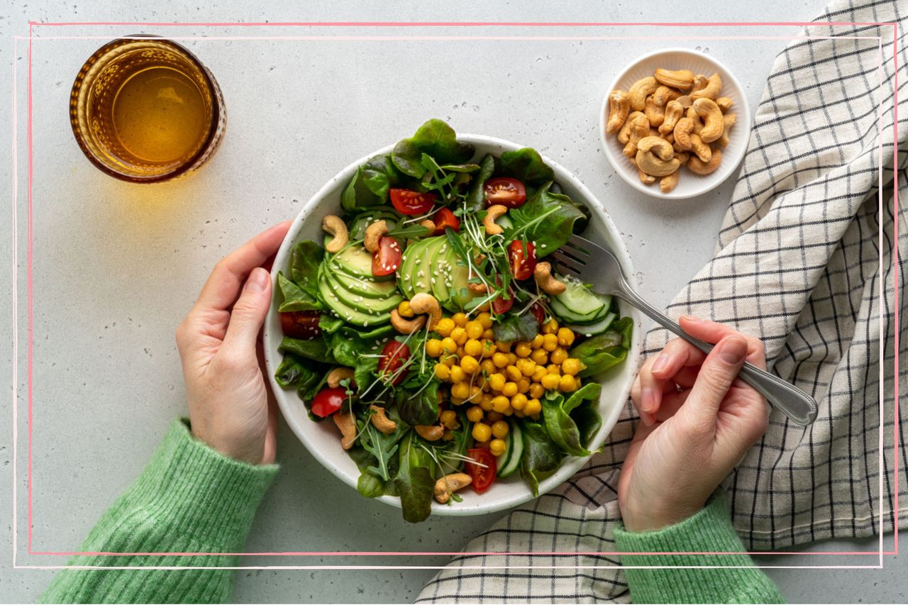 A large salad next to a bowl of nuts and glass of water