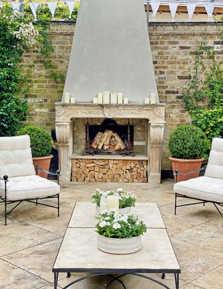 Outdoor living room with fireplace and stone flooring with seating