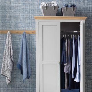 A room with blue and white wallpaper and a grey wardrobe