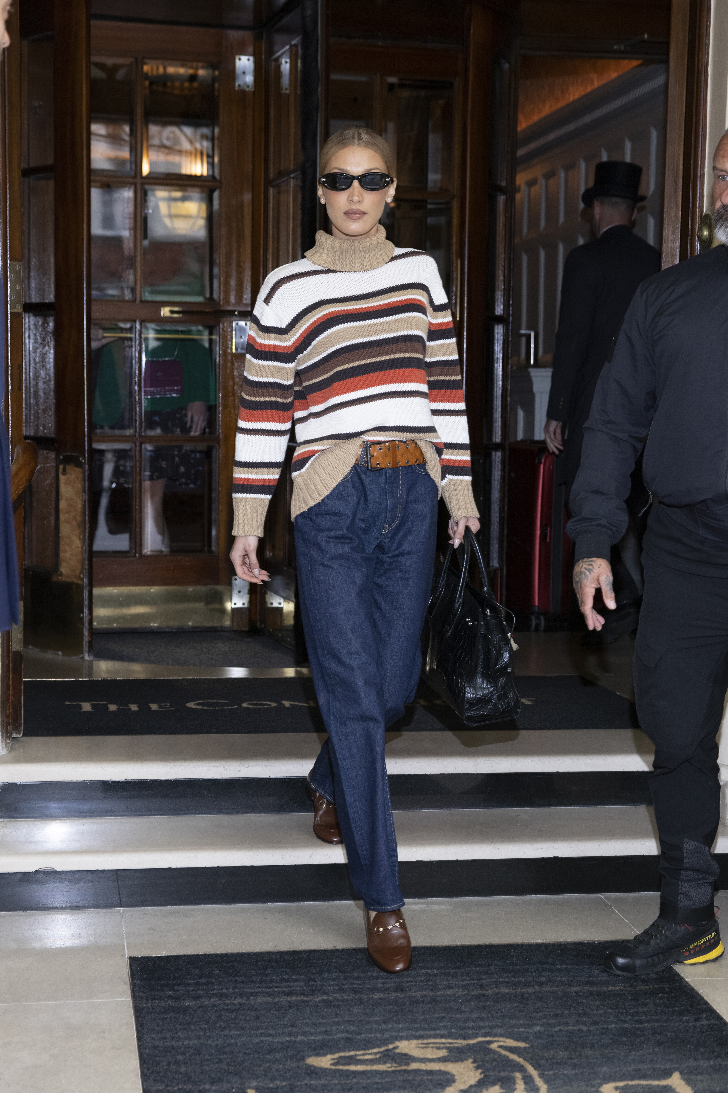 bella hadid wearing a striped sweater, jeans, and boots