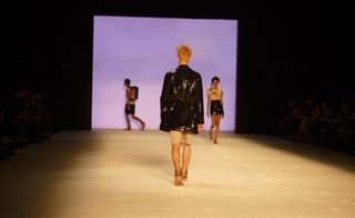 Models on a runway displaying glossy PVC and rubber-effect fabrics