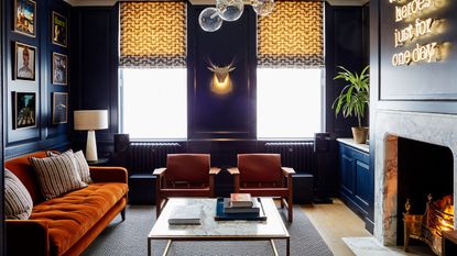 Cozy sitting room with fire lit, dark walls and orange velvet sofa