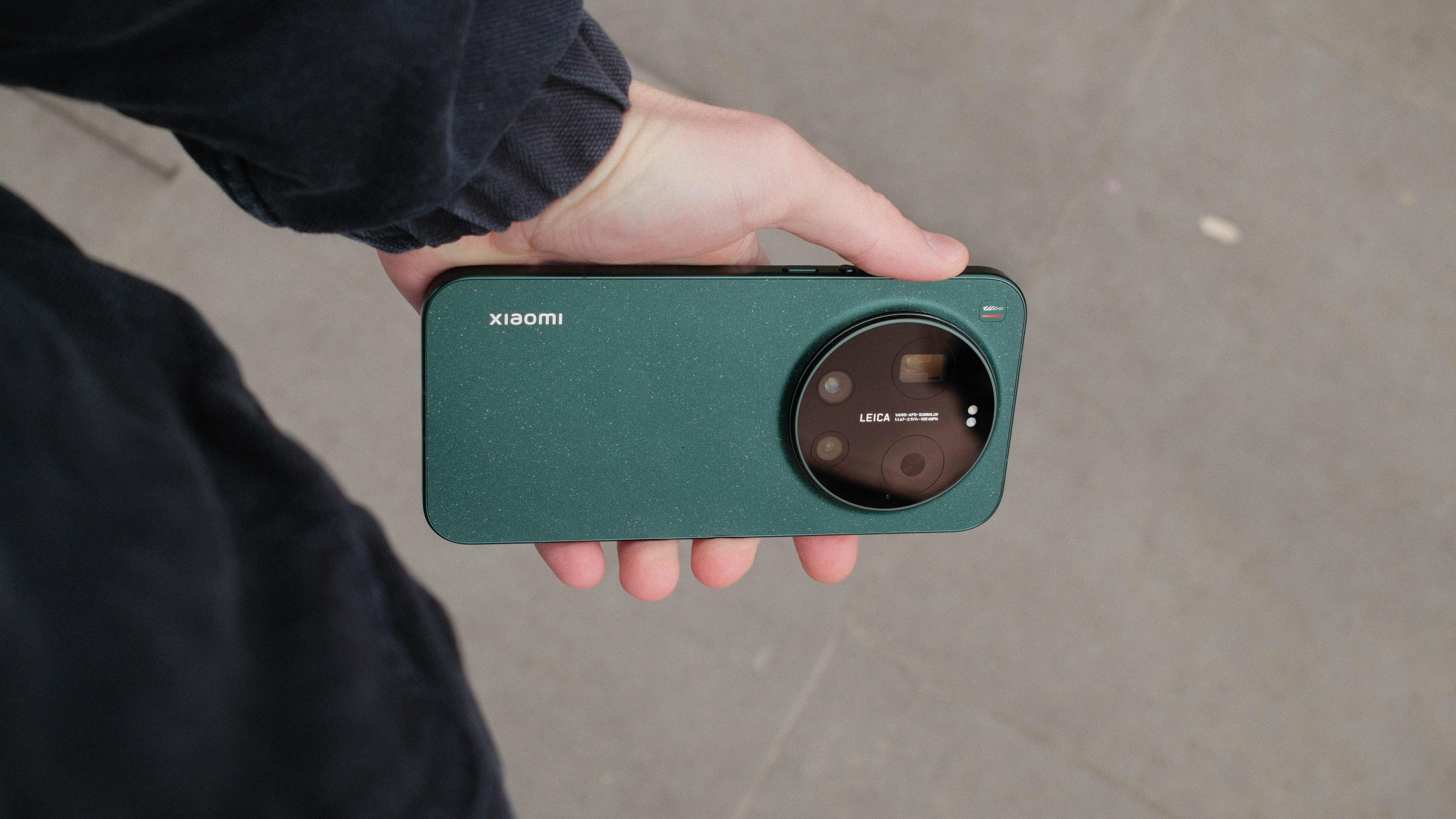 Hand holding the Xiaomi 17 Ultra horizontally, showing the large Leica camera module and green textured rear design.