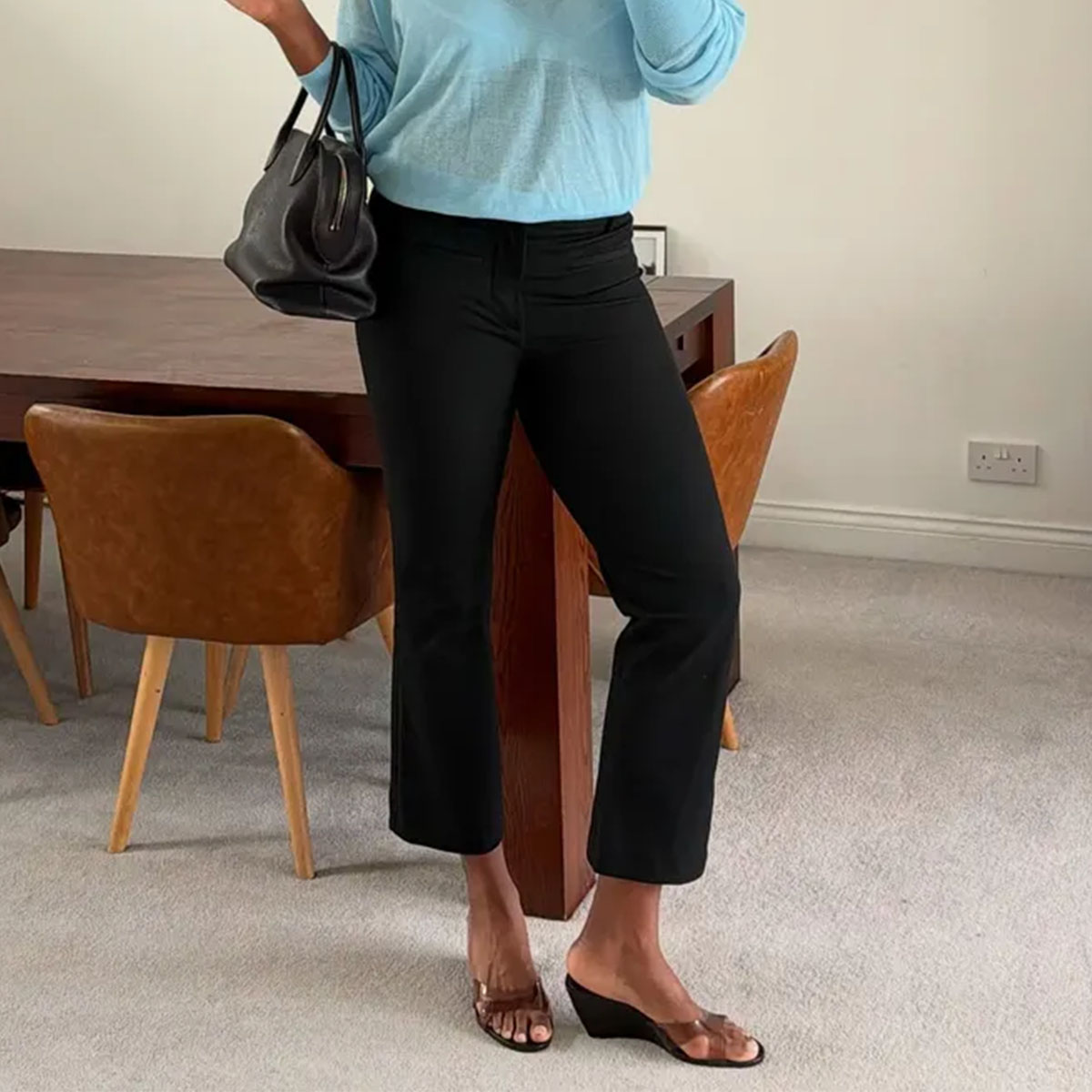 Woman in a blue sweater, black capris, and wedge sandals