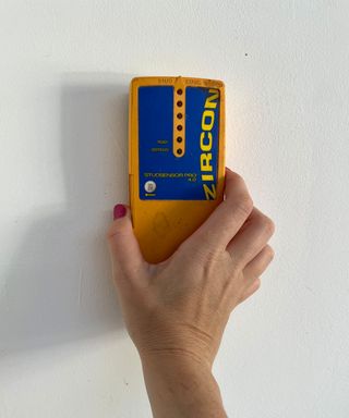 Womans hand with stud finder trying to find a stud