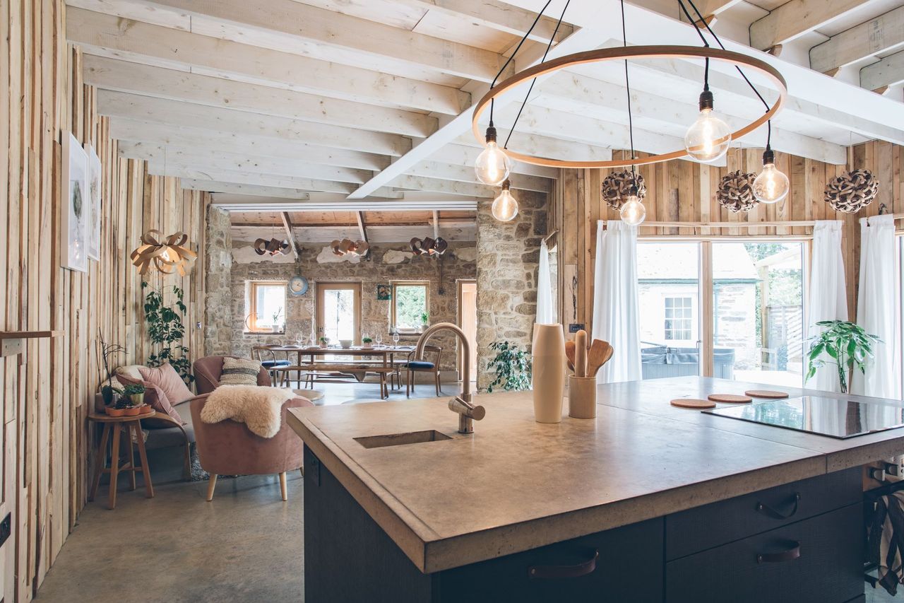 The kitchen-diner has a stone island and timber and stone walls and a long lounge area