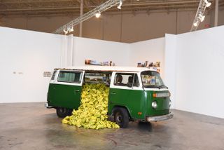 A green old-style VW van with the doors open and the van filled with bananas.