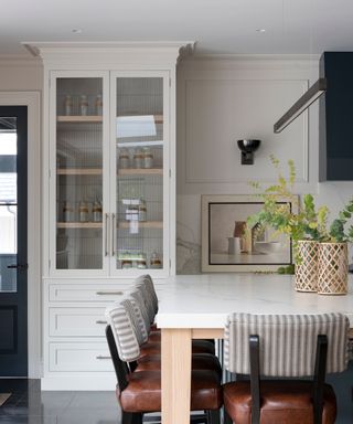 kitchen with off white cabinets, glazed cabinet, island and leather and striped barstools