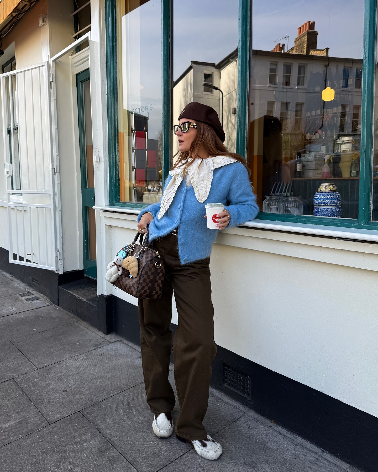 Influencer @rebeccaferrazwyatt wears brown jeans with cow-print shoes and a blue cardigan.