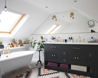 A loft bathroom with bespoke mirror, wide bathroom vanity and white freestanding bath