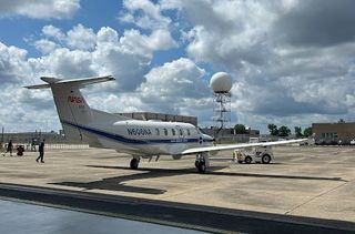 a small white plane on a concrete pad.