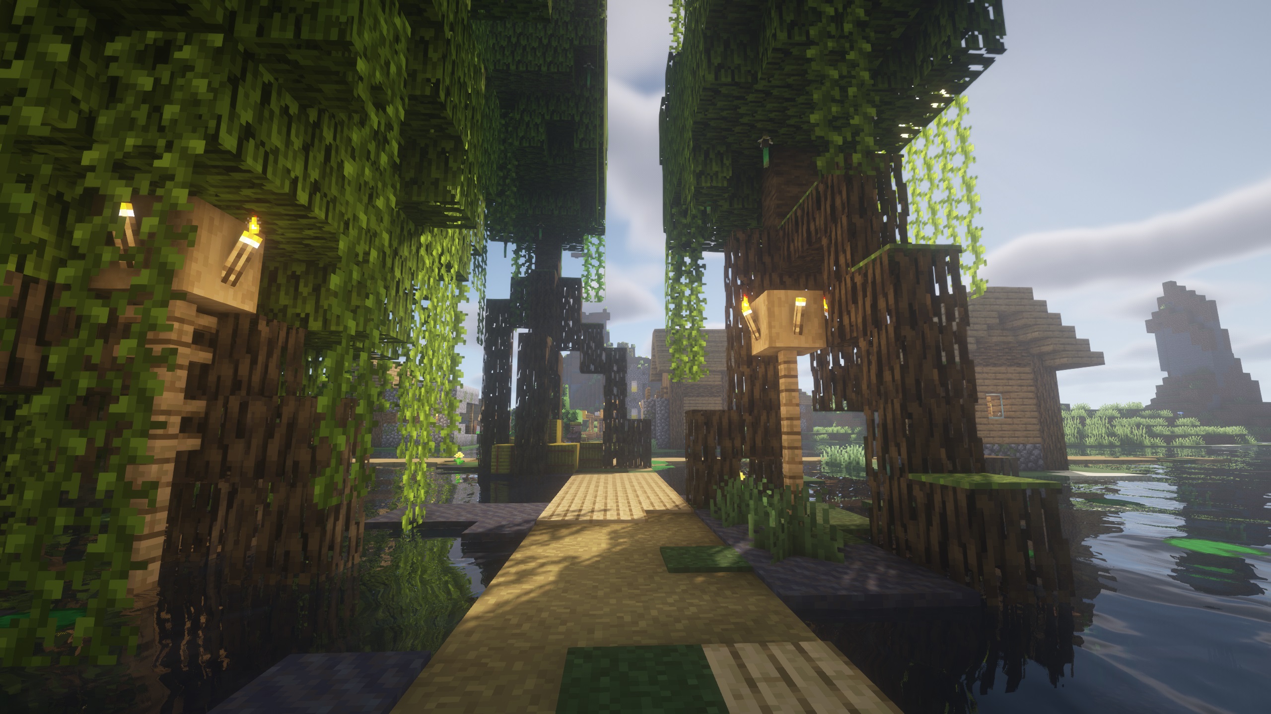 Minecraft seed - Mangrove tree roots growing over top of a wooden path leading to a small village