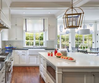 A white kitchen with a sheer curtain dressing the window